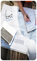 Building certifier reviewing construction blueprints, documents, and laptop on a site visit